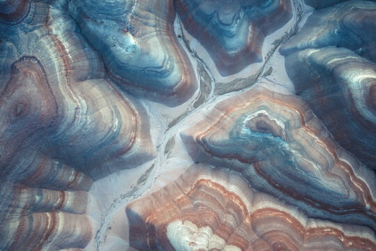 Aerial view of layered earth tones intertwine like brushstrokes on a canvas, creating a mesmerizing geological masterpiece, Hanksville, Utah, United States.