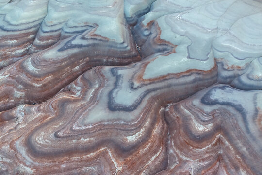 Aerial view of the undulating, layered formations of candy-colored rock, revealing nature's artistry in contrasting hues and textures, Hanksville, Utah, United States.