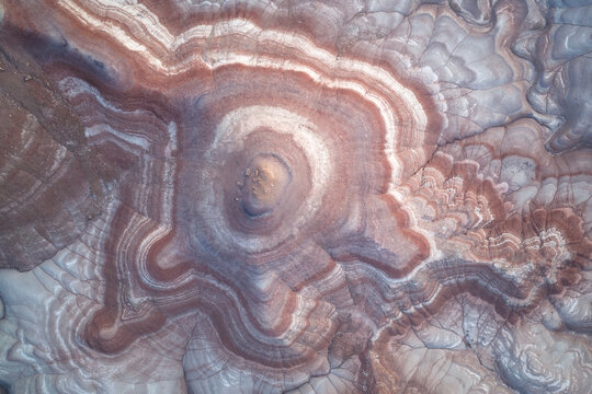 Aerial view of the mesmerizing concentric rings of earth tones swirling around a central peak, creating a natural masterpiece of geological artistry, Hanksville, Utah, United States.