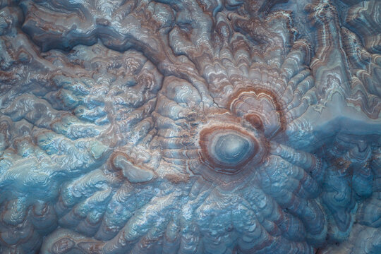 Aerial view of the textured, layered earth, sculpted by time and elements, reveals a tapestry of pale blues and rusty browns, Hanksville, Utah, United States.