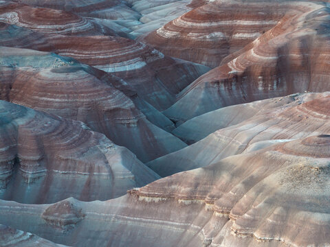 Aerial view of layered earth tones create a painterly landscape, where shadows accentuate the undulating terrain., Hanksville, Utah, United States.