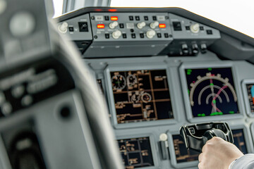 Fototapeta premium Pilot Hand on Throttle with Cockpit Instruments Blurred in Background