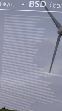 Vertical video: Cam panning turbine entering, wind turning blades, UI showing FX graph for finance
