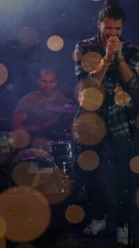 Vertical video: Male singer holding mic singing to link music fans as drum keeping beat amid bokeh