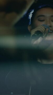 Vertical video: Female singer bringing mic singing music arm blocking then clearing lowering mic