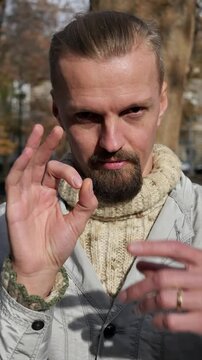 young lustful handsome man making gestures with fingers. Handsome young man laughing and playfully hinting at relationships. Boldness and lack of complexes. Openness in thoughts and actions