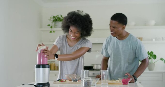 African American couple placing blender cup chopping fruit making pink smoothie for two in kitchen
