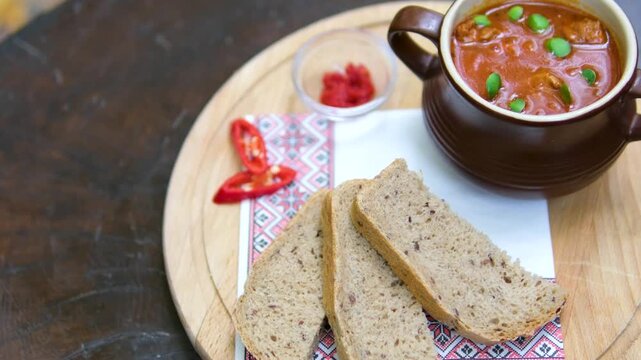 Vibrant traditional red soup likely Ukrainian borscht served with bread slices on a wooden surface. Rich beet base with greens and optional sour cream. 