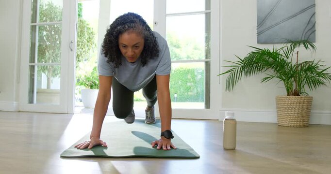 Green exercise mat absorbing knee-drive impacts on floor near glass doors, starting for cardio