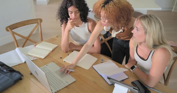 Standing woman tapping laptop trackpad and pointing, guiding seated women writing study notes