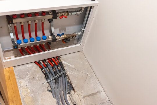 Heating pipes routed from floor into manifold cabinet showing distribution system during upgrade