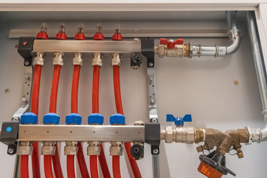 Heating manifold with multiple connected pipes inside cabinet showing residential distribution system