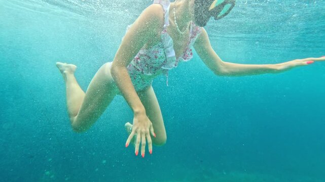 Female swimmer in mask snorkeling in clear blue tropical ocean water