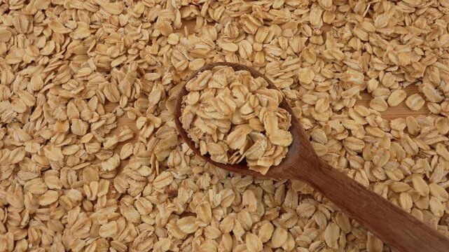 Dry uncooked oat flakes top view. Rolled oats in a wooden spoon.