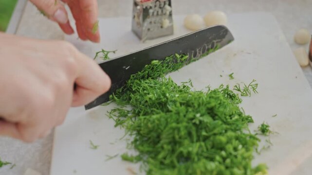 Fresh parsley being finely chopped quickly. Knife skillfully mincing parsley on bright outdoor table. Efficient outdoor cooking preparation with precise chopping of fresh parsley for camping meal