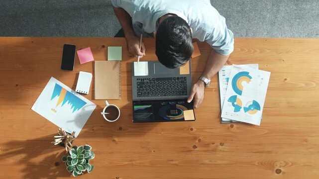Smart manager working on laptop with team walking and sitting at meeting table. Caucasian leader planning and analyzing financial data analysis at computer while colleague start working. Convocation.