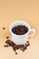 Obraz premium A white coffee cup with coffee beans, against on cream background.