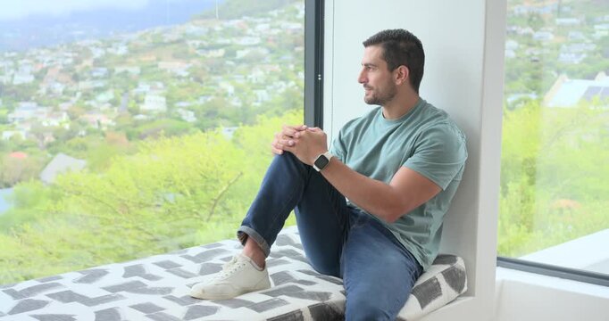 Shifting man in teal tee folding hands on home-seat, camera moving closer causing smile, copy space