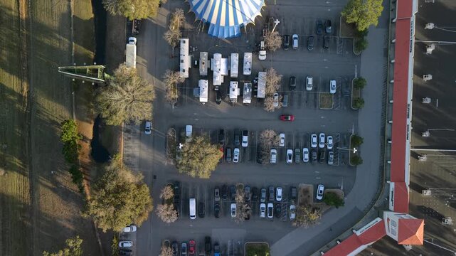 Aerial view of blue and white circus tents amidst a parking lot filled with cars and RVs, presenting a vibrant contrast, St. Augustine, Florida, United States.