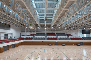 Spacious indoor sports hall with court markings and red stands © Namsun