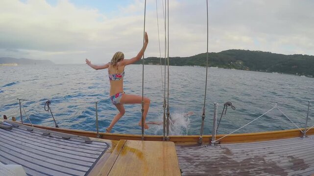 Friends, women and boat for jump in ocean, travel holiday activity and tropical adventure for bonding trip. Slip, back and people on yacht for vacation fun, spring break and swimming in sea together