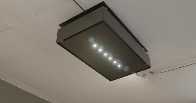 Modern black island extractor hood with LED lighting mounted on a white ceiling in a luxury kitchen