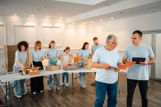 Volunteers cooperating packing donation boxes in distribution center