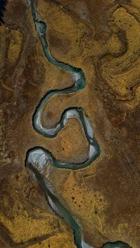 Aerial view of a serpentine river meanders through ochre landscapes, its cool, turquoise waters carving a path through the warm earth, Preda Rossa, Lombardia, Italy.