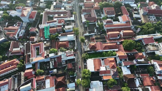 Aerial top down view of a dense residential neighborhood with red tiled roofs and a central street.