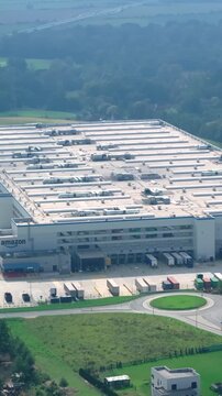 Amazon distribution center in Germany with delivery trucks parked around. Vertical video.