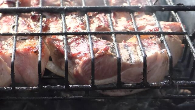 Meat is fried in a grill. The barbecue is large-scale, sizzles, roasts and cooks.