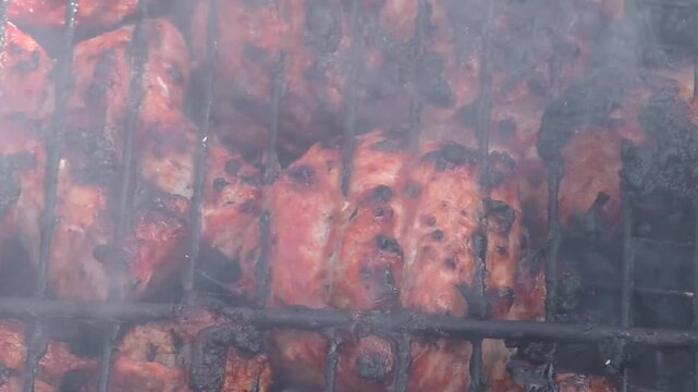 Meat is fried in a grill. The barbecue is large-scale, sizzles, roasts and cooks.