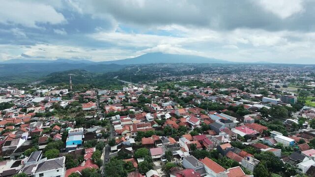 Aerial drone view of a dense urban city with a large volcano mountain in the background.