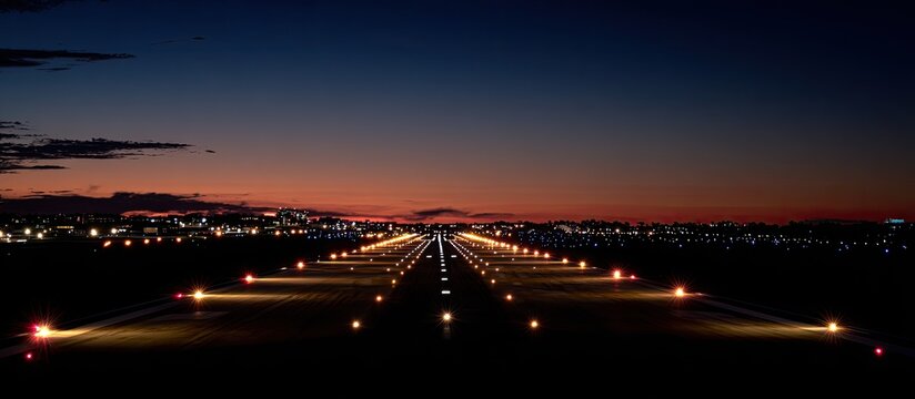 Night view of an illuminated airport runway stretching into the distance at sunset