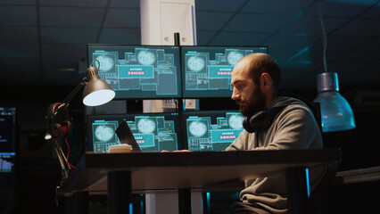 Aggressive violent hacker trying to hack network in office, feeling mad about hacking system failure. Dealing with hardware error trying to steal server information, irritated thief. Handheld shot. © DC Studio