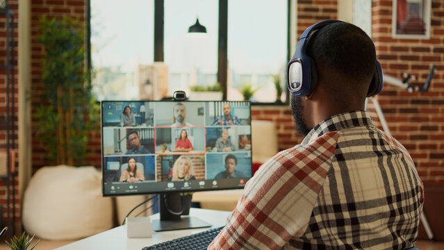 Startup worker attending online videocall meeting at home, talking to colleagues on teleconference call. Using webcam on videoconference to chat, work from home remotely at desk.
