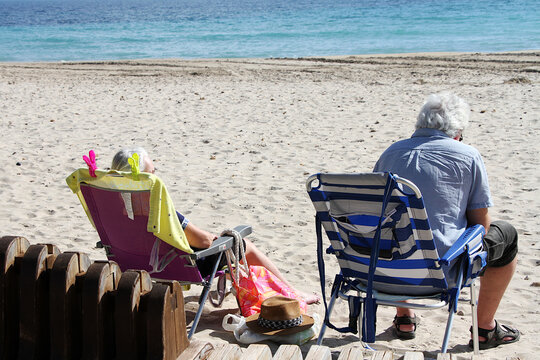Pareja en la playa tomando el sol en silla tumbona junto al mar en vacaciones de verano