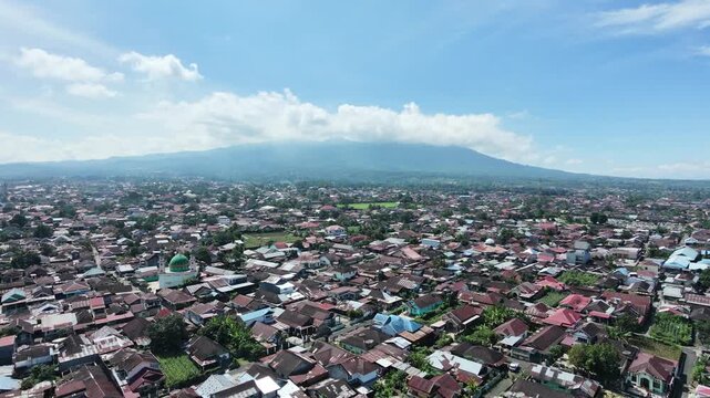 Aerial drone shot of Sungai Penuh city in Jambi Indonesia with Mount Kerinci in the background.