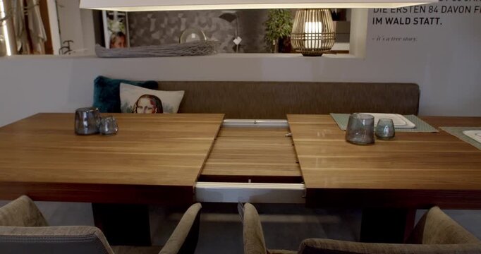 Modern extendable wooden dining table in a luxury furniture showroom with minimalist interior design