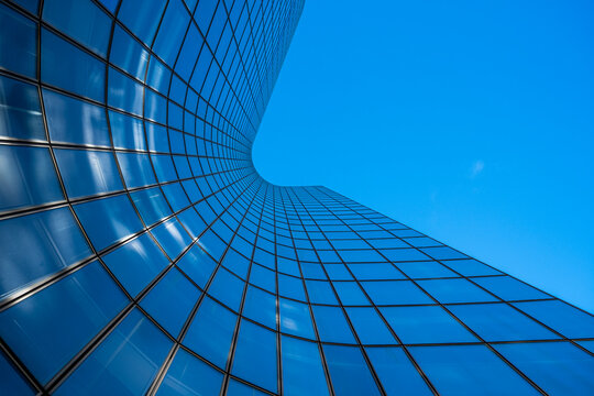 Abstract perspective of modern glass building facade with reflection in grid under open sky presents architecture geometry in minimalist style