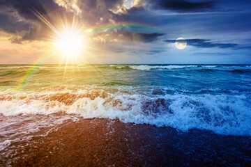 stormy weather on the sandy beach. day and night time change concept. dramatic sky over the sea with sun and moon. moody landscape on autumn equinox. majestic cloudscape above the horizon