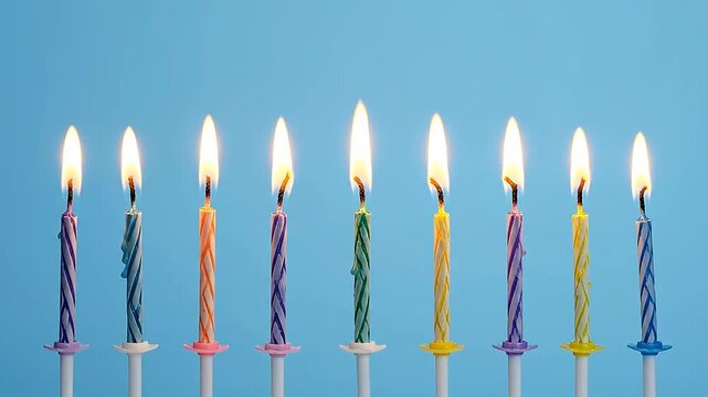 A row of colorful birthday candles with glowing flames on a blue background