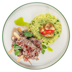 Naklejka premium Grilled meat skewers with green couscous, zucchini and chili on plate isolated background. Gourmet restaurant dish for menu design.