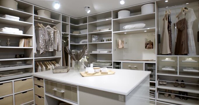 Modern luxury walk-in closet with white shelving integrated island and organized storage space