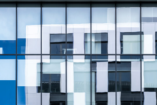 Blue glass building facade with grid windows pattern and geometry expressing modern architecture detail for editorial style office backdrop