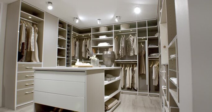 Modern luxury walk-in closet with white cabinetry central island and bright spotlight lighting