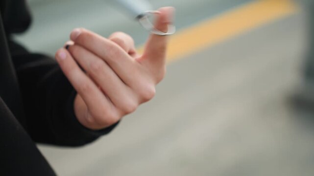 Teen performing finger illusions outdoors. Closeup of youthful hands with ring demonstrating finger tricks. Detailed shot of young person showing finger tricks with ring in city street background