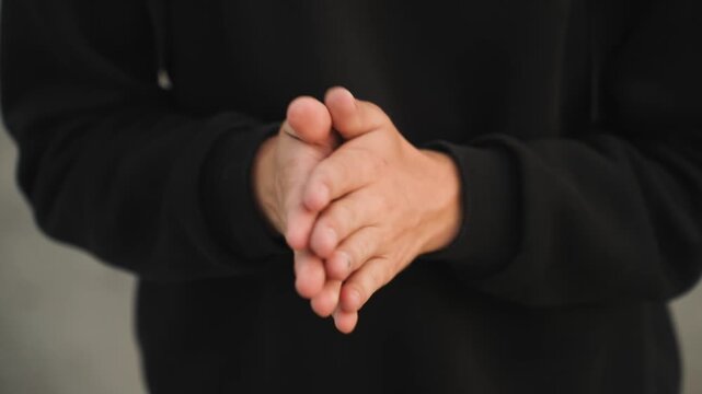 Close up hands fidgeting in hoodie, young adult rubbing fingers and palms in neutral indoor setting, subtle nail detail, casual black sweatshirt, sequence shows calming and anxious gestures, ideal