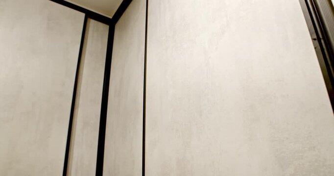 Modern minimalist closet front with light gray concrete texture and black metal frame detail