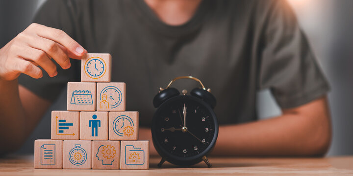 project manager organizes time management and productivity using wooden blocks with workflow icons and alarm clock. Concept of planning, efficiency, scheduling, performance control, work optimization